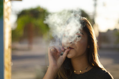 Portrait of young woman smoking cigarette outdoors