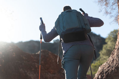 Woman climbs the mountain in the garraf natural park, supported by hiking sticks.