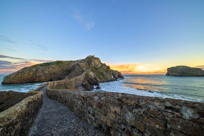 Rocks on beach against sky during sunset