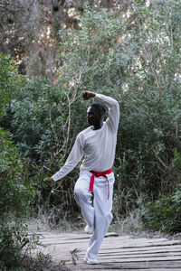 Adult man practicing martial arts in forest