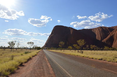 Road by mountains against sky