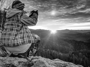 Hiker woman photographer takes impresive photos from sharp cliff edge. bw, black and white,