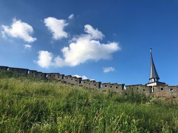 Buildings on field against blue sky