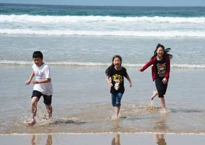 Full length of happy children running on beach