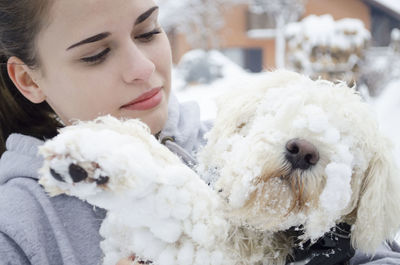 Portrait of young woman with dog on snow