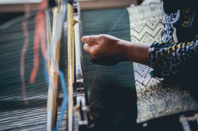 Midsection of woman weaving textile at loom