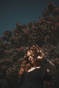 Woman standing by tree against sky