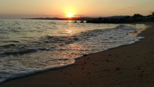 Surf reaching on shore at beach during sunset