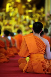 Rear view of monks sitting at temple