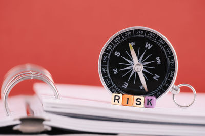 Close-up of navigational compass and risk text on book against red background