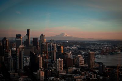 Aerial view of city buildings against sky during sunset