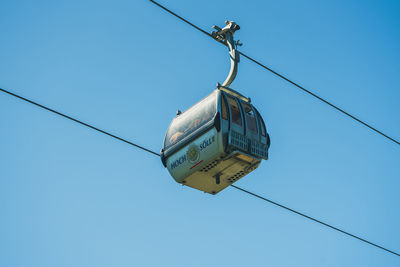 Low angle view of overhead cable car against blue sky