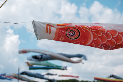 Low angle view of fish flags hanging against sky