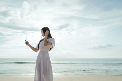 Woman standing at beach against sky