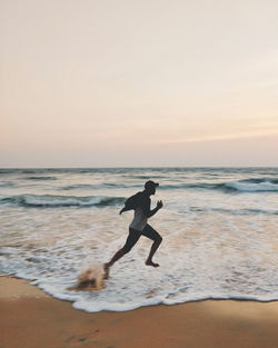 Man on beach against sky during sunset