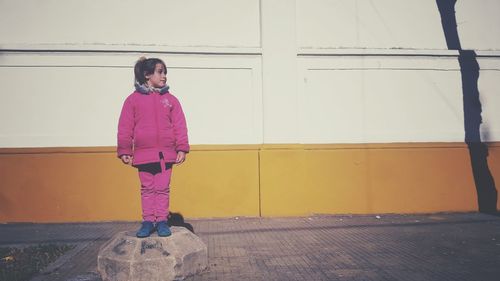 Young woman standing against wall