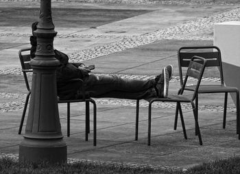 Side view of man sitting on bench in park