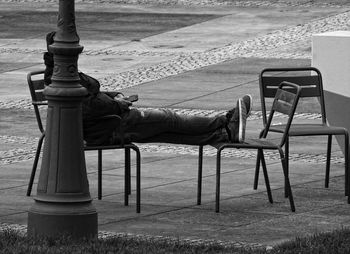 Side view of man sitting on bench in park