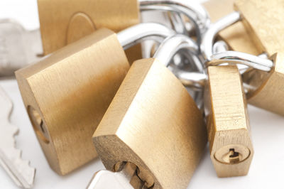 Close-up of golden padlocks and keys on white background