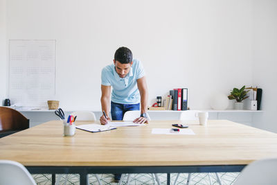 Young businessman standing at desk looking trough files