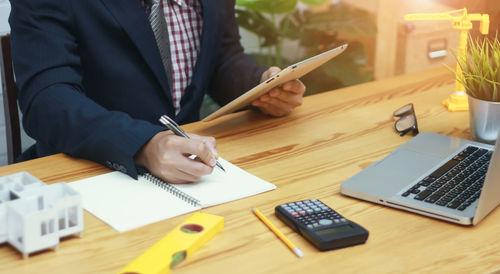 Midsection of man using mobile phone while sitting on table