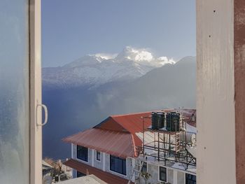 Houses by mountain against sky during winter