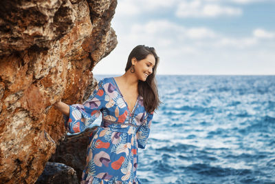 Young woman in summer dress at cliff waterfront on mallorca