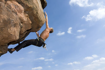 Low angle view of man on rock against sky