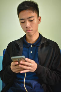 Portrait of young man holding camera over gray background