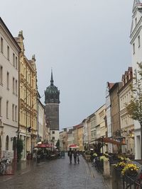 People walking in city against clear sky