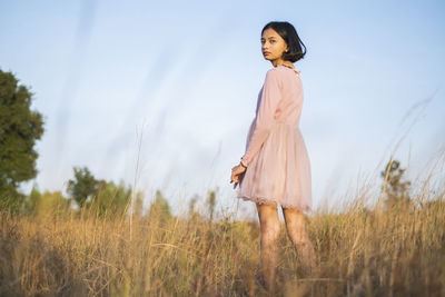 Woman standing on field against sky