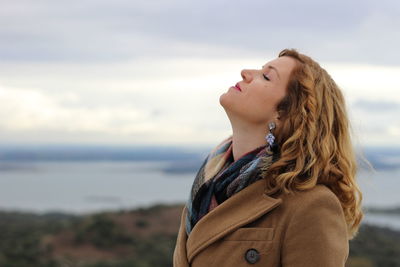 Young woman with headback standing on mountain against sky during sunset