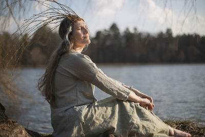 Close up woman in slavic pagan outfit sitting on lake coast portrait picture