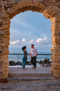 Rear view of friends on sea shore against sky