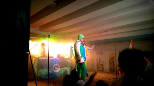 Man standing against illuminated lighting equipment at night