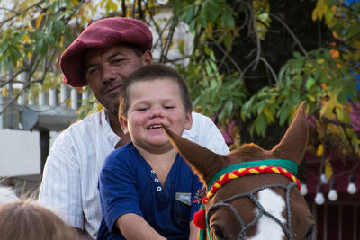 Father and son sitting on horse outdoors