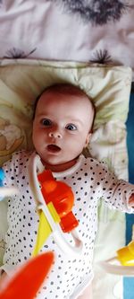 Portrait of cute baby girl lying on bed