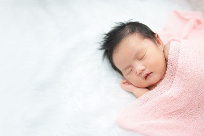 High angle view of cute baby girl sleeping on bed at home