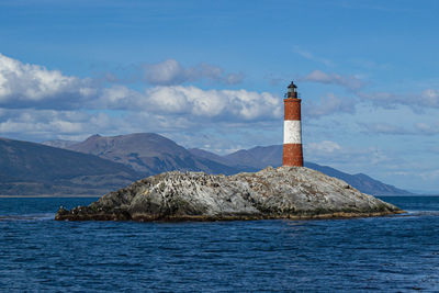 Lighthouse by sea against sky