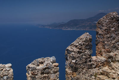 Rock formations by sea against blue sky