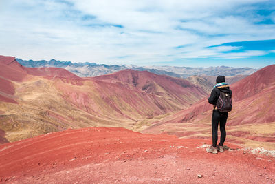 Rear view of man standing on mountain against blue sky