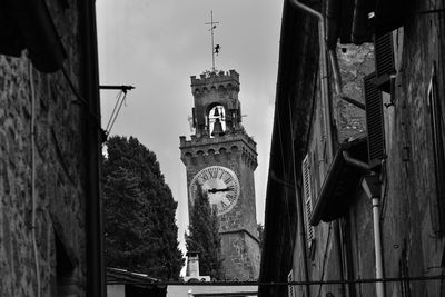 Low angle view of clock tower amidst buildings against sky