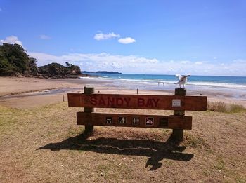 Close-up of text on beach against sky