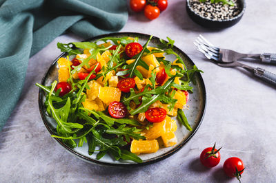 Dietary salad of orange slices, cherry tomatoes and arugula on a plate on the table