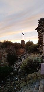 Cross in cemetery against sky during sunset