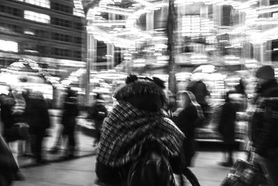 Rear view of people walking on city street at night