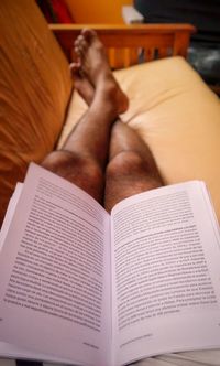 Midsection of person reading book at home