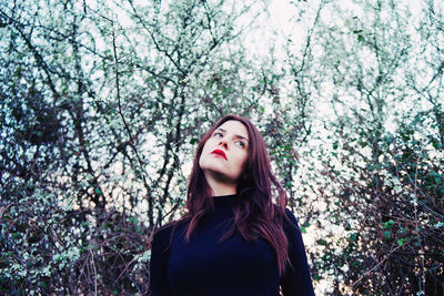 Young woman standing against tree