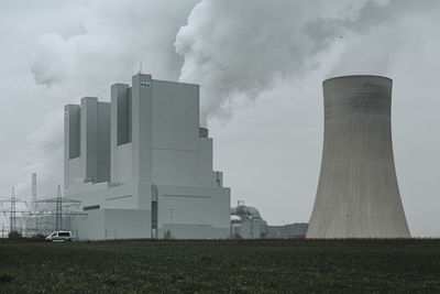 Smoke emitting from factory against sky