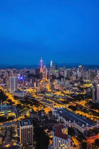 Illuminated cityscape against blue sky at night